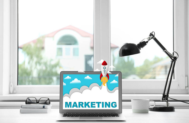 Digital marketing concept. Modern laptop and lamp on table near window indoors - Photo, Image