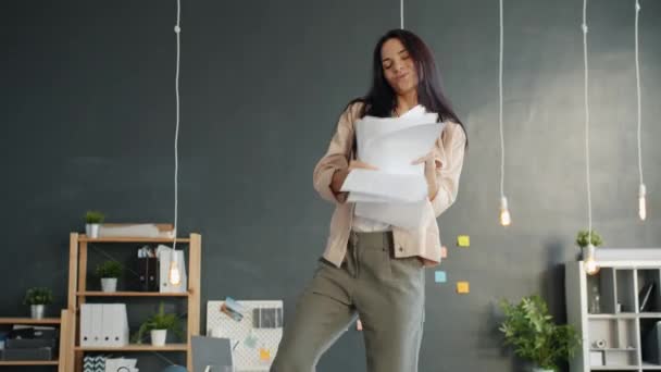 Happy office worker dancing on table throwing papers enjoying music and freedom - Záběry, video