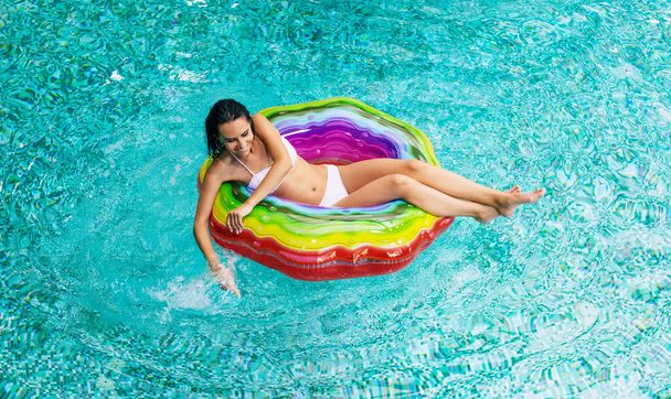 Top view photo of enjoying suntan excited woman in bikini on the inflatable mattress in the swimming pool. Summer Vacation. Relaxing in the Hotel pool  - Fotoğraf, Görsel
