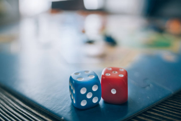 Board game and dice close-up. Game cubes on a wooden table and on the background of a colorful, vibrant game board - Fotoğraf, Görsel