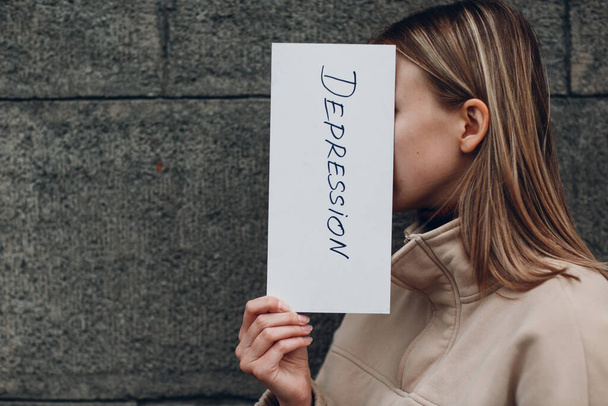 Mujer sostiene en hoja de papel con la palabra Depresión
 - Foto, Imagen