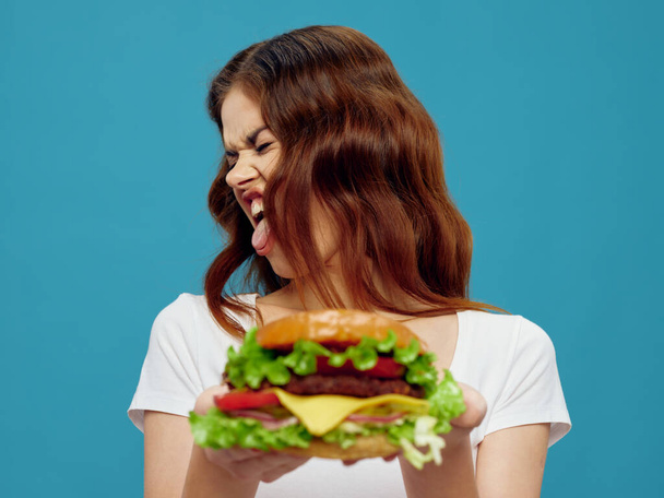 Cheerful emotional woman shows hamburger tongue close-up  - Foto, Imagen
