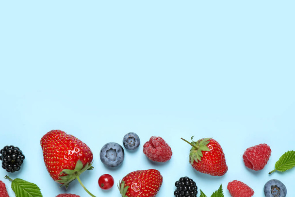 Different fresh berries on light blue background, flat lay. Space for text - Foto, immagini