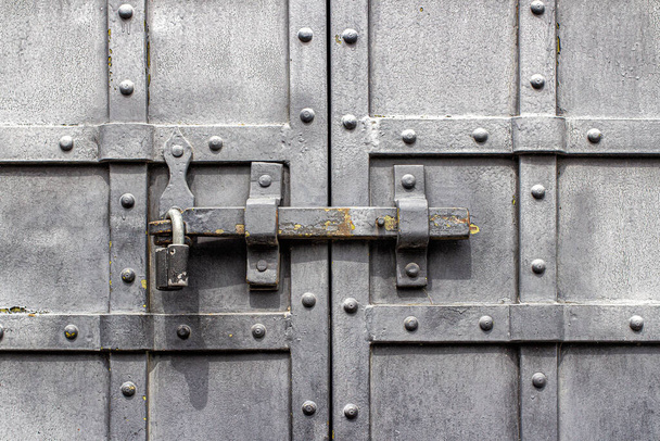 Czarne, kute metalowe drzwi z nitami i żelaznym zatrzaskiem - Zdjęcie, obraz