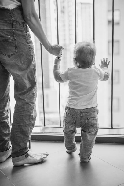 siluetti äiti ja vauva ikkunan edessä, mustavalkoinen kuva, käsite vauvan turvallisuutta. Naisten äitiysvapaa, eristäytyminen karanteenissa - Valokuva, kuva
