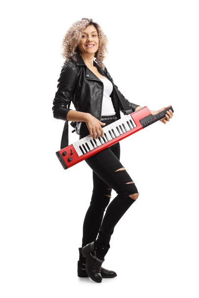 Full length portrait of a woman in leather clothing playing a keytar synthesizer isolated on white background - Foto, Imagem