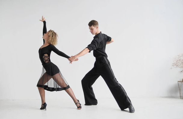 Piękna para w stylowych czarnych kostiumach tańczy taniec towarzyski - Zdjęcie, obraz