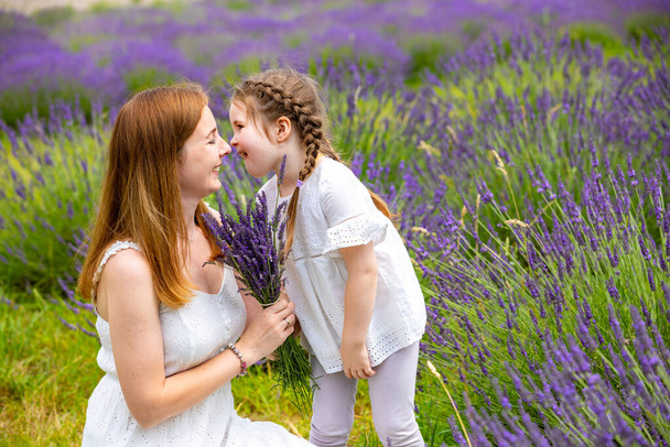 Mother walks with her little daugher holding a bouquet of lavander in Czech republic - Photo, image