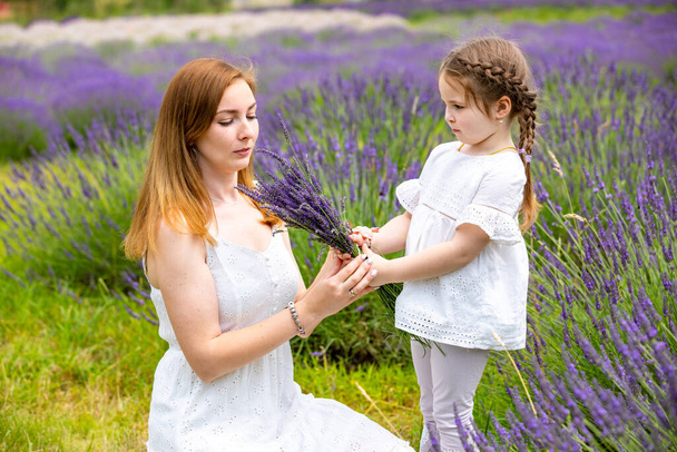Mother walks with her little daugher holding a bouquet of lavander in Czech republic - Photo, Image