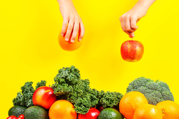Χέρια μαζεύοντας μήλα και πορτοκαλιές από σωρό φρέσκα λαχανικά και φρούτα - Φωτογραφία, εικόνα