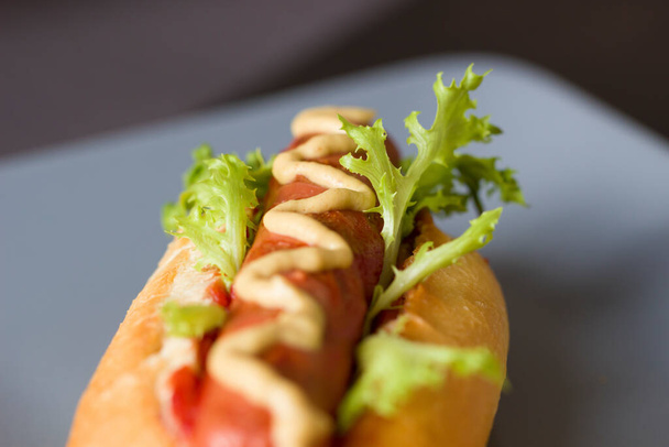 One homemade classic hot dog with yellow mustard, ketchup and green salad.American Fast Food. National holiday hot dog Day. close-up.Low depth of field. - Foto, Imagen