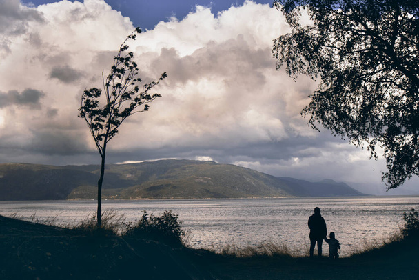 Силуети матері та її сина, які дивляться на фіорд у Норвегії. - Фото, зображення
