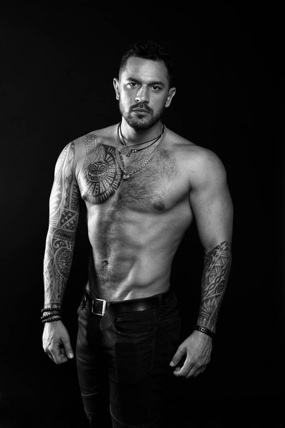 Macho sexy bare torso. Fit model with tattoo art skin. Sportsman or athlete with beard and hair. Sport and fitness. Masculinity. Muscular torso. Jewelry for real men. Bearded man with tattooed torso - Foto, immagini