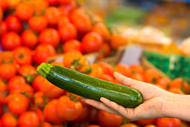 Female hand choosing zucchini in supermarket. Concept of healthy food, bio, vegetarian, diet. - 写真・画像
