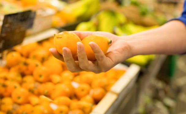 Woman's hand choosing medlar fruit in the market. Concept of healthy food, bio, vegetarian, diet. - Фото, зображення