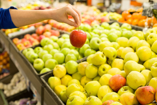 Mano de mujer eligiendo manzana en el mercado. Concepto de alimentación saludable, bio, vegetariano, dieta
. - Foto, imagen