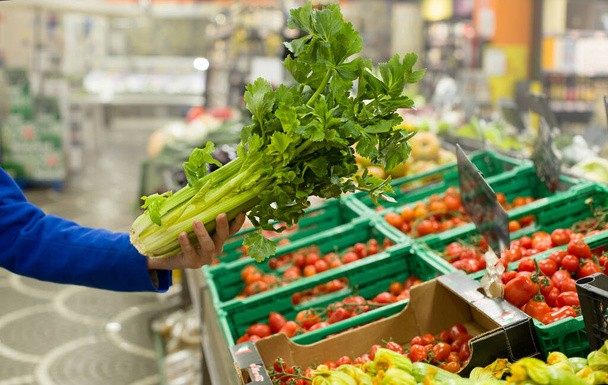 La mano de la mujer eligiendo apio en el supermercado. Concepto de alimentación saludable, bio, vegetariano, dieta
. - Foto, Imagen