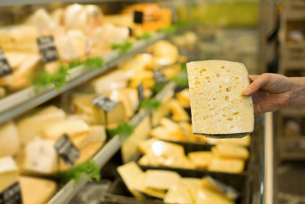 Woman's hand choosing cheese in supermarket. Concept of healthy food, bio, vegetarian, diet. - Photo, Image