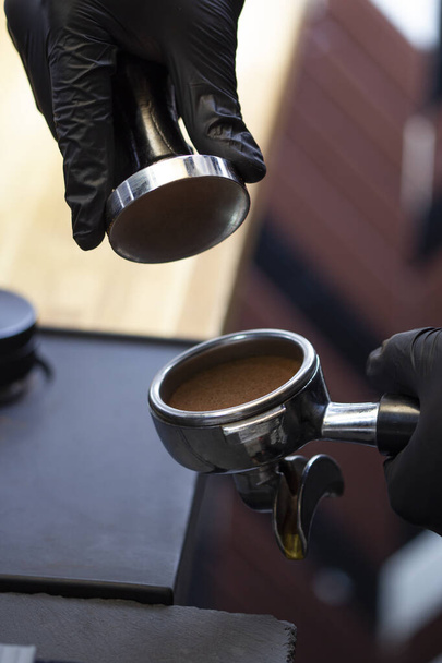 Barista making presses the coffee in the portafilter with temper - Φωτογραφία, εικόνα