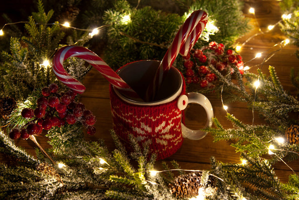 Taza blanca de té en una caja roja de punto, dulces de Navidad y bayas sobre un fondo de decoración de Año Nuevo - Foto, imagen