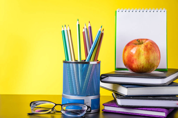 Torniamo al concetto di scuola. Forniture scolastiche, mele e libri su sfondo giallo. Posto per testo. - Foto, immagini