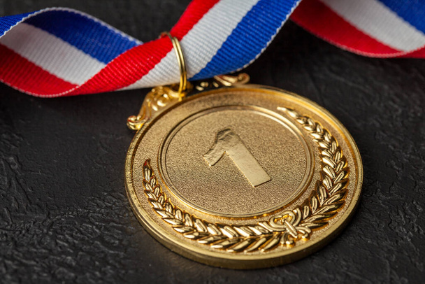 リボン付きゴールドメダル。競技会で1位を獲得。チャンピオンへの賞。黒の背景 - 写真・画像