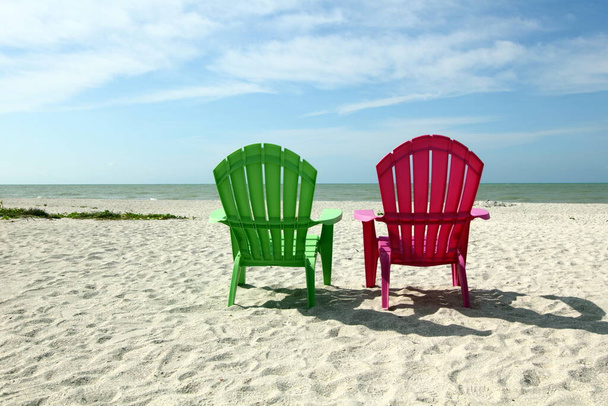 Adirondack strandstoelen met zeezicht op witte zandkust - Foto, afbeelding