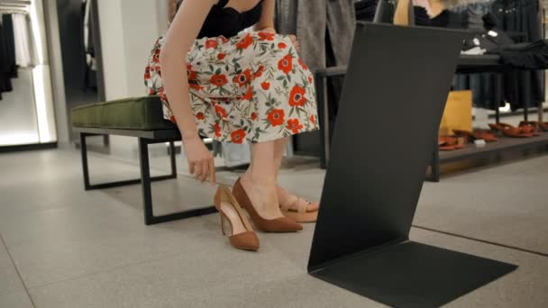 La fille essaie des chaussures dans le magasin de vêtements du centre commercial - Séquence, vidéo