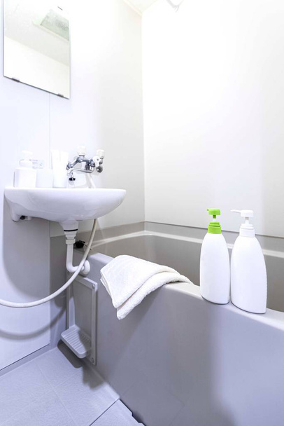 Крупним планом пластикові пляшки для шампуню та крему для душу, розміщені на краю ванни
 - Фото, зображення