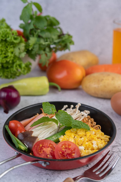 Mieszać smażony makaron, który łączy kukurydzę, grzyby złotej igły, pomidory, kiełbasę, edamame i cebulę na patelni. - Zdjęcie, obraz