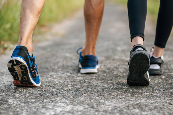Corredor mujer y hombre pies corriendo en la carretera primer plano en zapato. Concepto de estilo de vida saludable deportivo
. - Foto, imagen