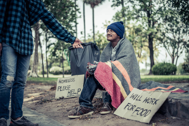 Bedelaars gewikkeld in stof en zetten dan een hoed op en gingen naast de straat zitten en iemand gaf geld.. - Foto, afbeelding