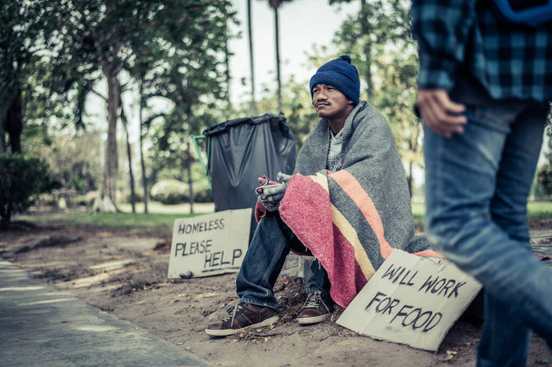 Beggars wrapped in cloth and then put on a hat and sat down beside the street and someone gave money. - Photo, Image