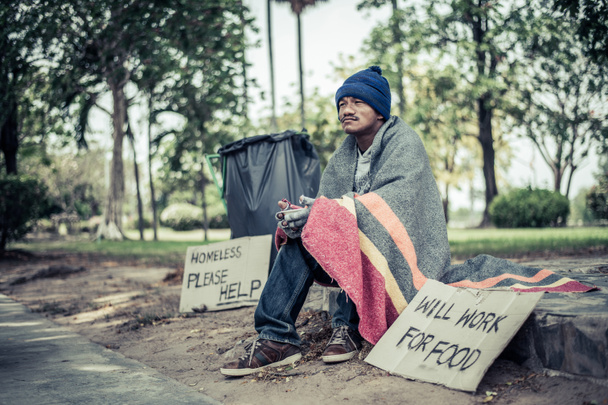 Beggars, wrapped in cloth, then wearing a hat and sitting down beside the road. - Photo, Image
