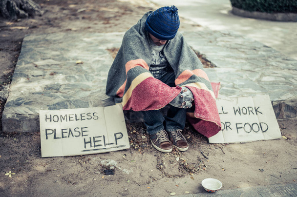 Beggars, wrapped in cloth, then wearing a hat and sitting down beside the road. - Foto, Imagen