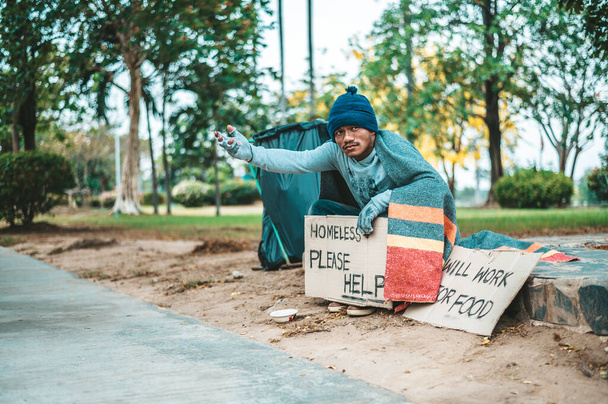 Мужчина, сидящий попрошайничает с бездомными, пожалуйста, помогите. Селективный фокус. - Фото, изображение