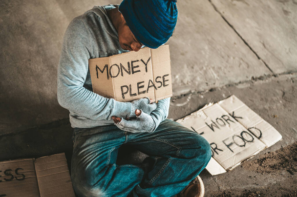 Beggars sitting under the bridge with a sign, please money. - Photo, Image
