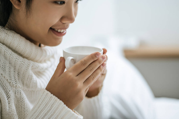 Eine Frau hielt eine Tasse Kaffee und lächelte glücklich. - Foto, Bild