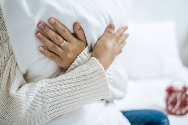 Incrociare le mani e sedersi, abbracciare un cuscino bianco sul letto. Focus selettivo - Foto, immagini