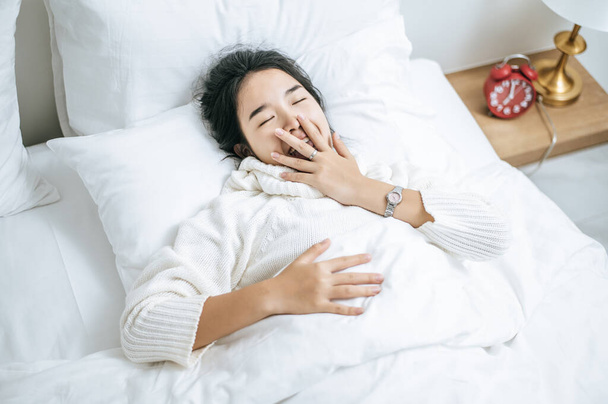 Vrouw met wit shirt slapend op bed en witte kussens. - Foto, afbeelding