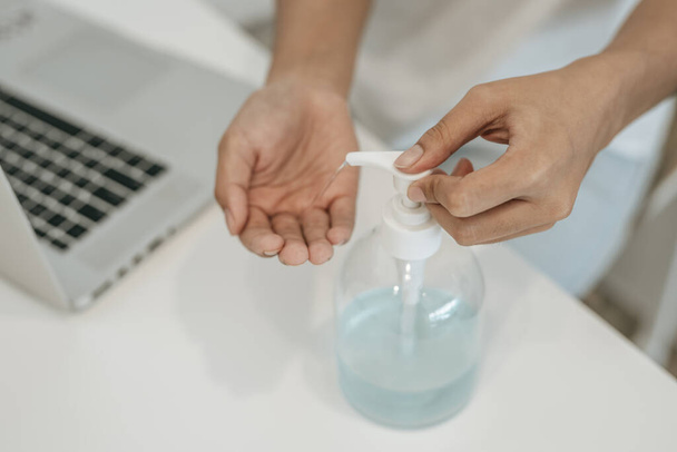 Mujeres que usan camisas blancas que presionan el gel para lavarse las manos para limpiarse las manos
. - Foto, Imagen