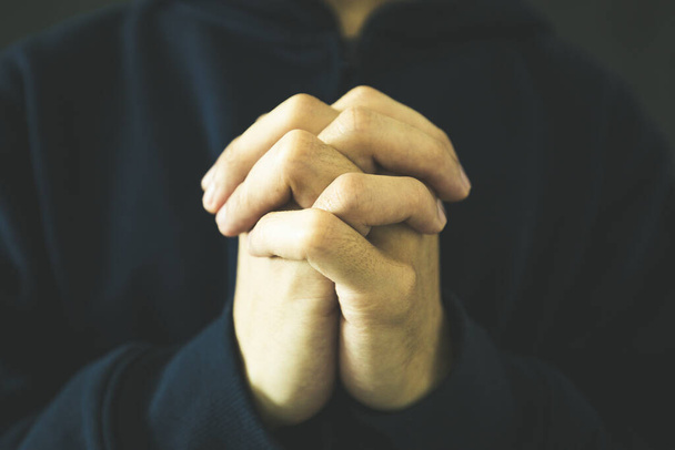 Christian faith towards God concept, Asian man christians worship and pray in church. Praying in dark black background. - Fotoğraf, Görsel