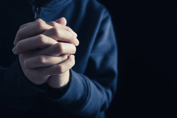 Christian faith towards God concept, Asian man christians worship and pray in church. Praying in dark black background. - Fotoğraf, Görsel