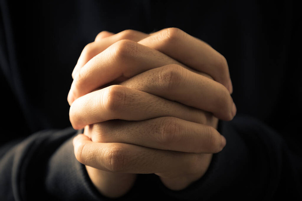 Christian faith towards God concept, Asian man christians worship and pray in church. Praying in dark black background. - Valokuva, kuva