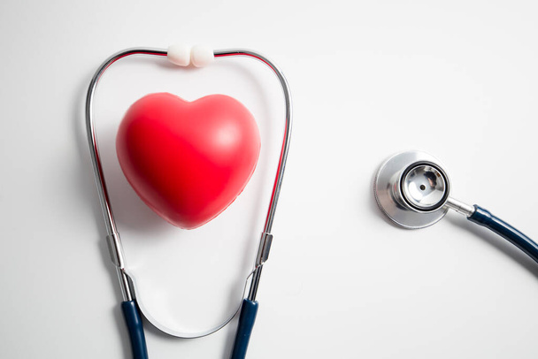 Rotes Herz mit Stethoskop auf weißem Hintergrund, Herzgesundheit, Krankenversicherungskonzept, Weltgesundheitstag. - Foto, Bild