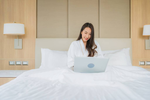 Portret mooie jonge aziatische vrouw gebruik laptop computer in slaapkamer interieur - Foto, afbeelding