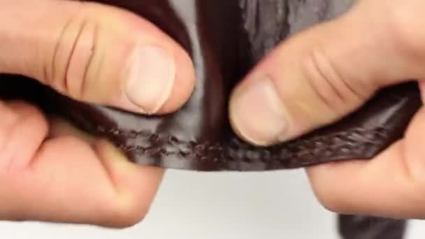 menselijke hand testen stuk van bruin natuurlijk glad glanzend glanzend leer met bruine naden, het buitenste deel en binnen, deel van de rugzak, controle van de kwaliteit van het product, close-up macro view - Video
