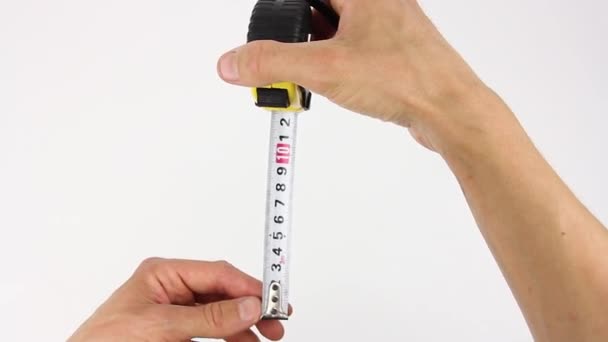 human hands pull the measuring tape out of tape measure and measure the dimensions, length width height and diagonal, close up view on white background - Footage, Video