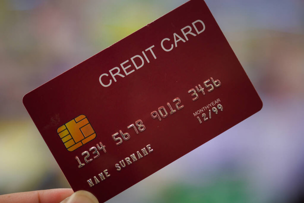 close-up fotografie van hand man met een rode creditcard - Foto, afbeelding