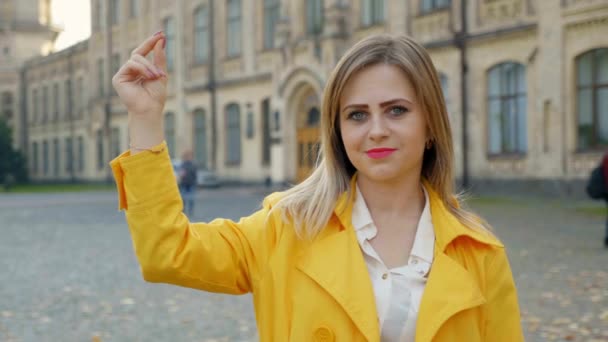 Pozitivní žena v bílé halence, žlutý plášť luskne prsty a usměje se - Záběry, video